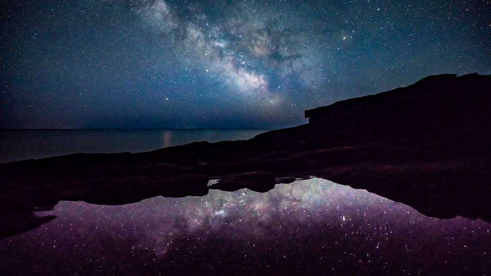 Milky Way and stars shine off the coast of Acadia National Park
