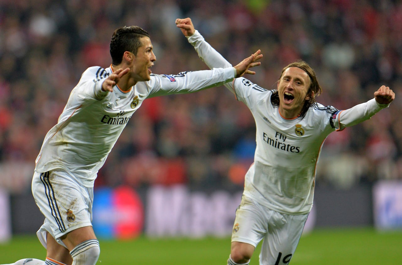 Luka Modric and Christiano Ronaldo of Real Madrid cheer on a soccer pitch in white jerseys