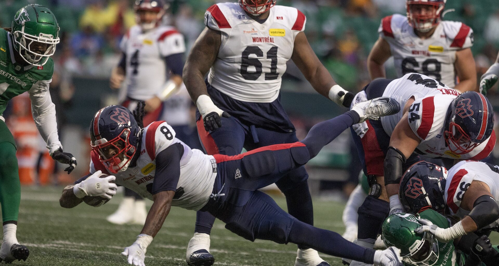 Football running back dives forward with the ball.