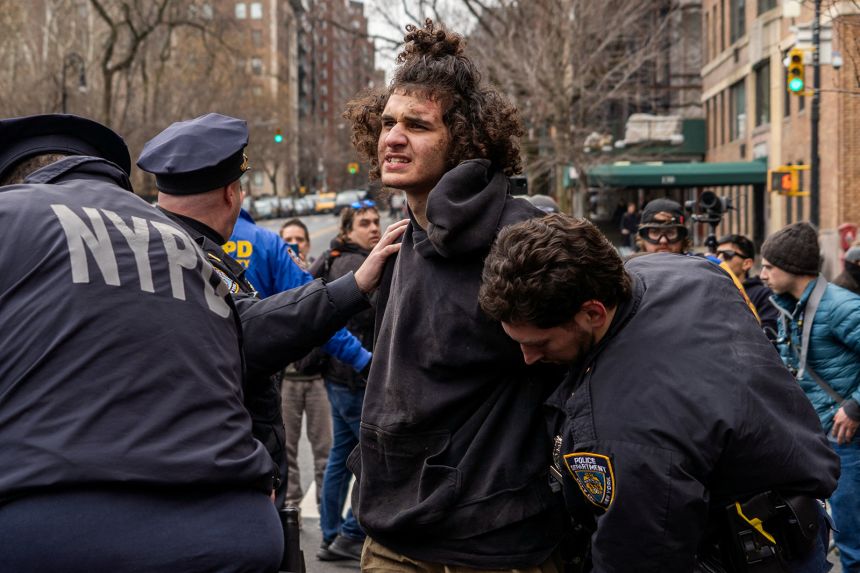 Counter-protester Emir Balat is detained by NYPD officers outside Gracie Mansion in New York City on March 7. Balat has pleaded not guilty to charges that include attempting to provide material support to a foreign terrorist organization and using a weapon of mass destruction.