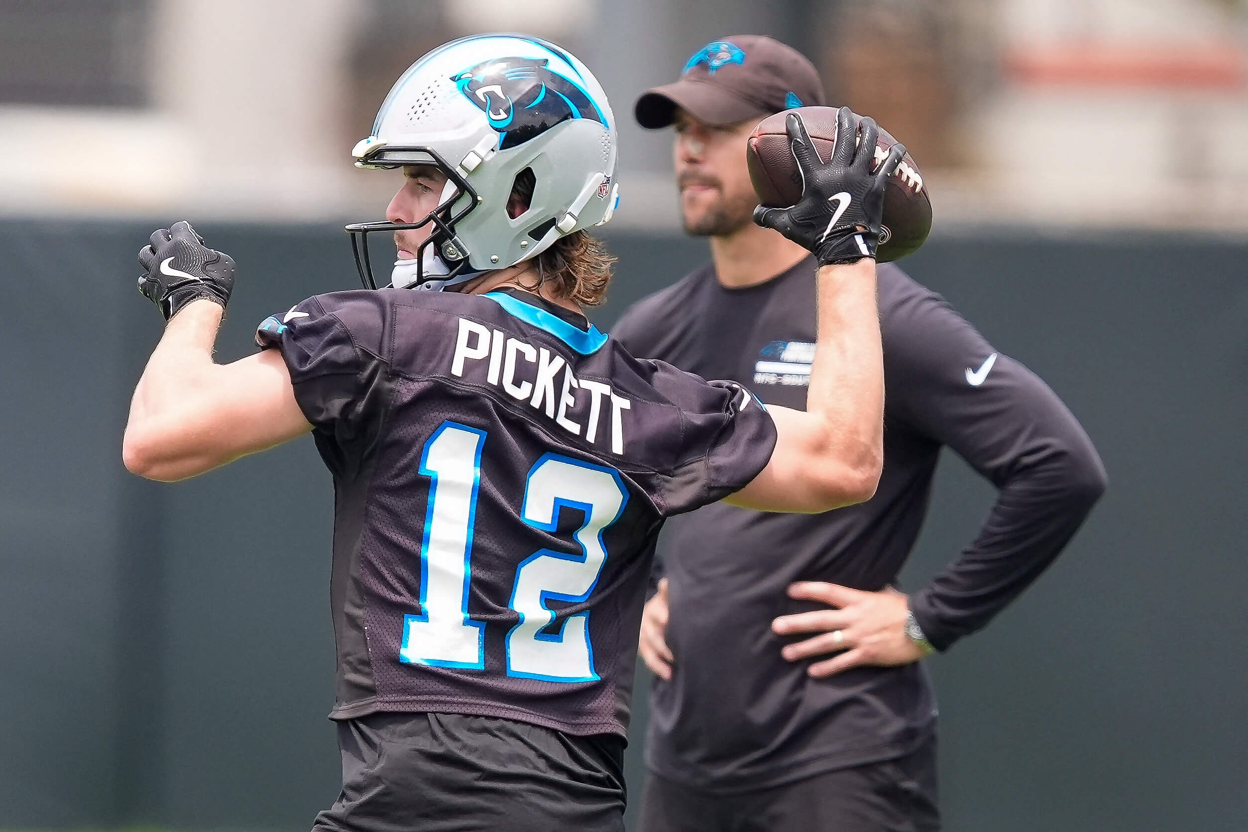 Carolina Panthers quarterback Kenny Pickett (12) throws watched by head coach Dave Canales during the first day of mini camp at Bank of America Stadium practice facility. 
