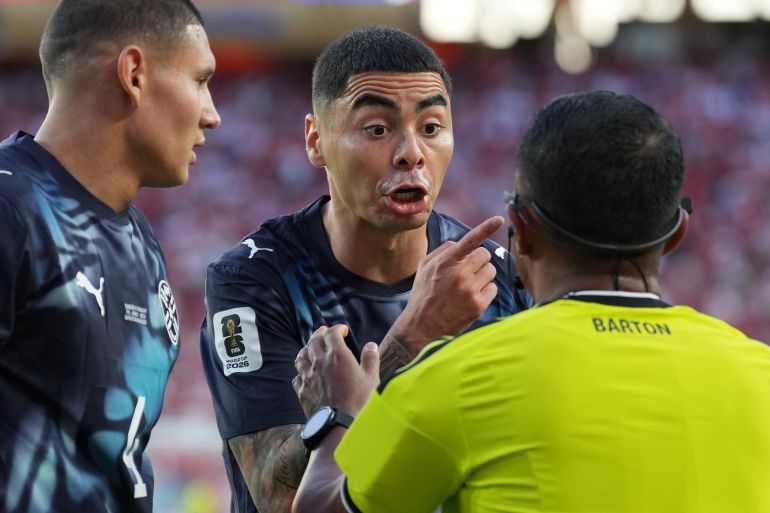 Jun 19, 2026; Santa Clara, California, USA; Paraguay midfielder Miguel Almiron (center) argues with referee Ivan Barton (right) with defender Juan Jose Caceres (left) during a Group D match of the 2026 FIFA World Cup at San Francisco Bay Area Stadium. Mandatory Credit: Darren Yamashita-Imagn Images