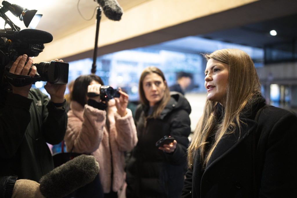 Amber Bracken speaks in front of journalists with cameras and microphones