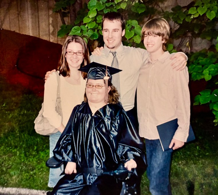 Rebecca Anger, center, is seated in a wheelchair while surrounded by three of her siblings, posing for a portrait outside