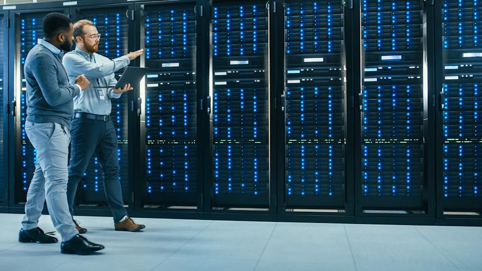 AI data center technicians are walking through racks of servers.