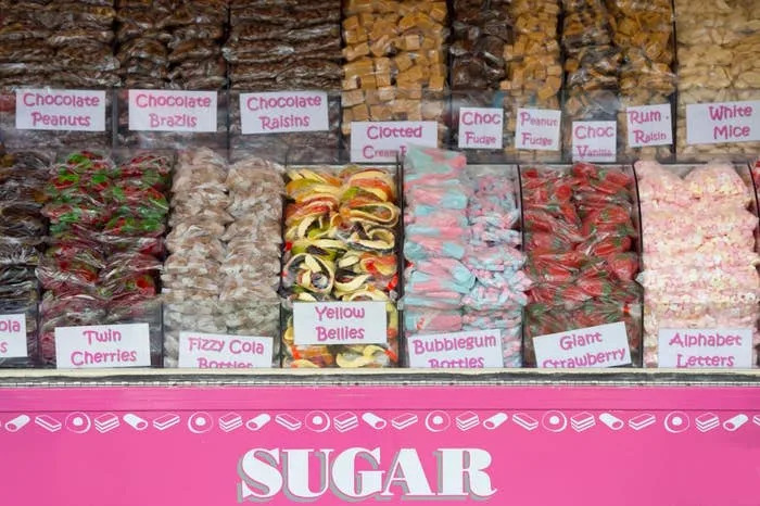 A window display showcasing a variety of sweets and candies, each labeled with its name