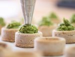 A master baker fills round dough molds made from field bean flour with a pea and wild garlic paste at the "Qioback" bakery. The Quendt family bakery produces only savory snacks without gluten-containing grains.