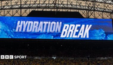 Television screen inside a stadium shows the words "hydration break" at the World Cup