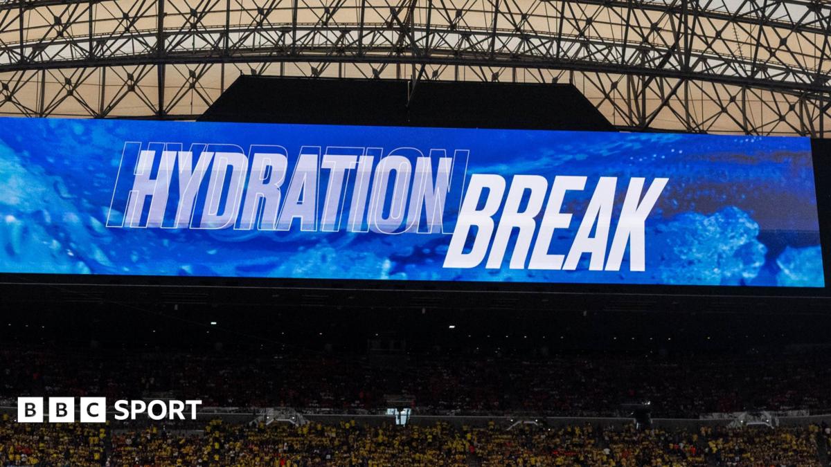 Television screen inside a stadium shows the words "hydration break" at the World Cup