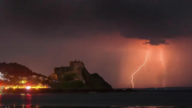 Two orange lightning strikes are seen in the sea next to Mount Orgueil Castle in Jersey