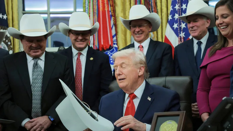 DECEMBER 12: U.S. President Donald Trump puts on a hat given to him by the 1980 U.S. Olympic men's ice hockey team as Trump honors the team in the Oval Office of the White House on December 13, 2025 in Washington, DC. Trump honored the 'Miracle on Ice' team, who defeated the Soviet Union and went on to win the 1980 Gold medal in Ice Hockey, by signing a bill to award the players congressional gold medals. (Photo by Anna Moneymaker/Getty Images)