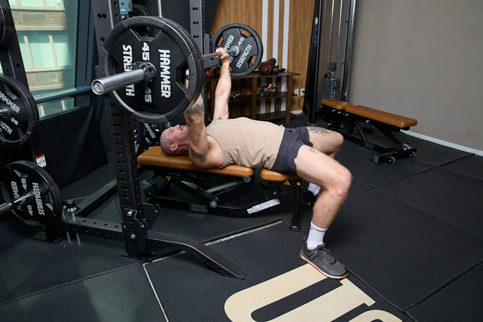 Man performing bench press in gym on weight bench.