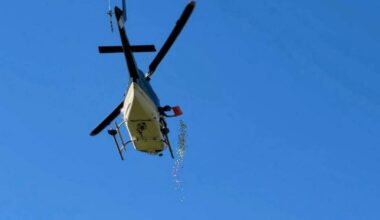A man from a helicopter drops hundreds of golf balls onto the driving range at the Okanagan Golf Club in Kelowna on June 18 (Brayden Ursel/Black Press)