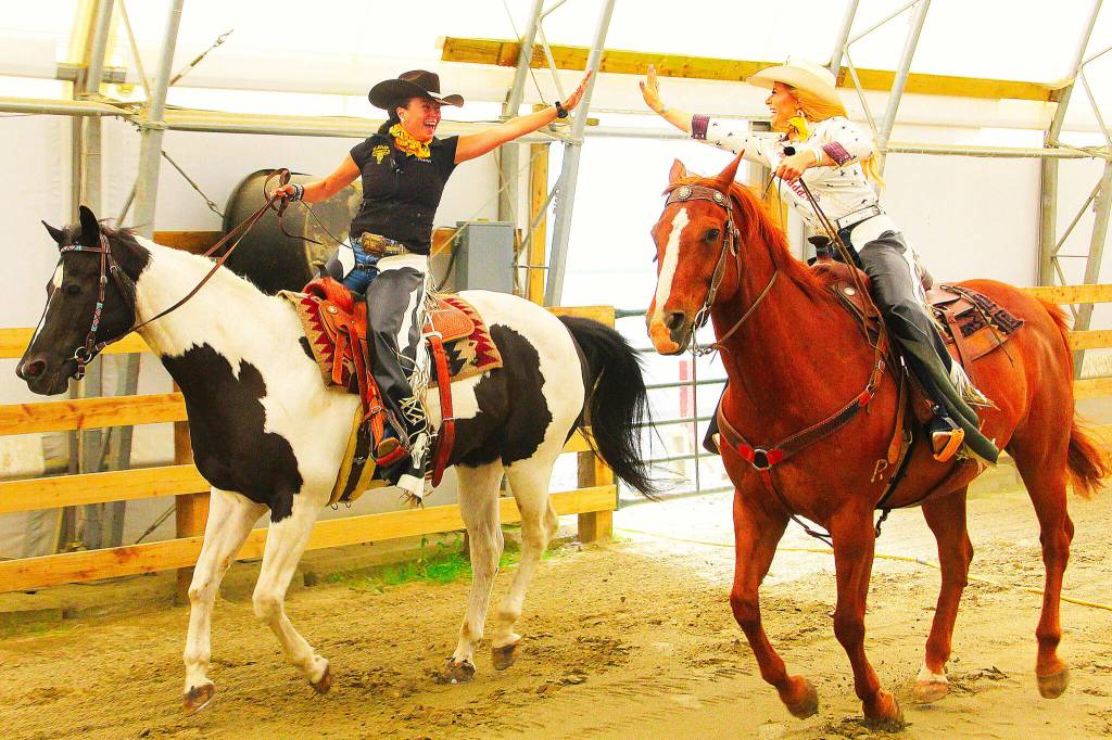 Sheila Hicks, president of Valley West Stampede (seen here on Par), and Abbey Harty, Miss Rodeo Canada 2026 (seen here on Red), high five during a promotional shoot for Valley West Stampede. (Photo: Malin Jordan/Cloverdale Reporter)
