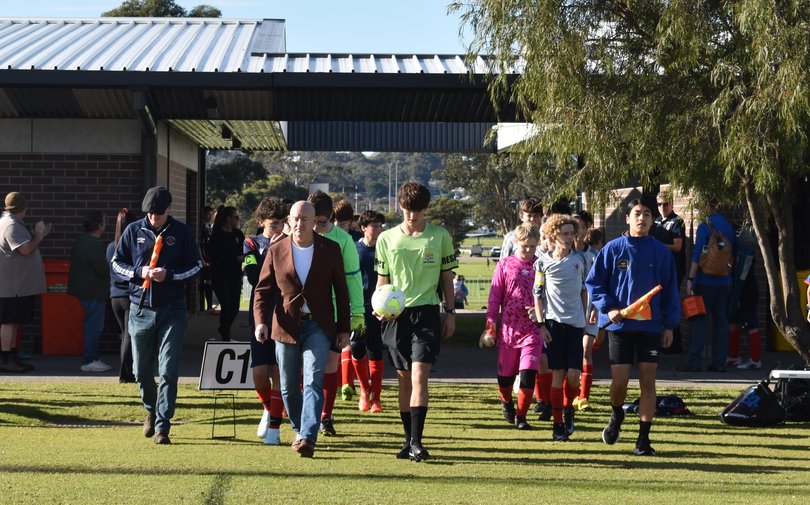 Scott Leary and the match officials lead out the teams. 