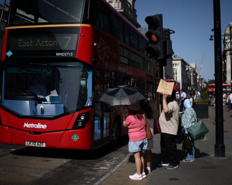 People use umbrellas and shopping bags to shield themselves from the sun while waiting to cross Oxford Street as Britain experiences record temperatures disrupting schools and transport networks, in London, Britain.