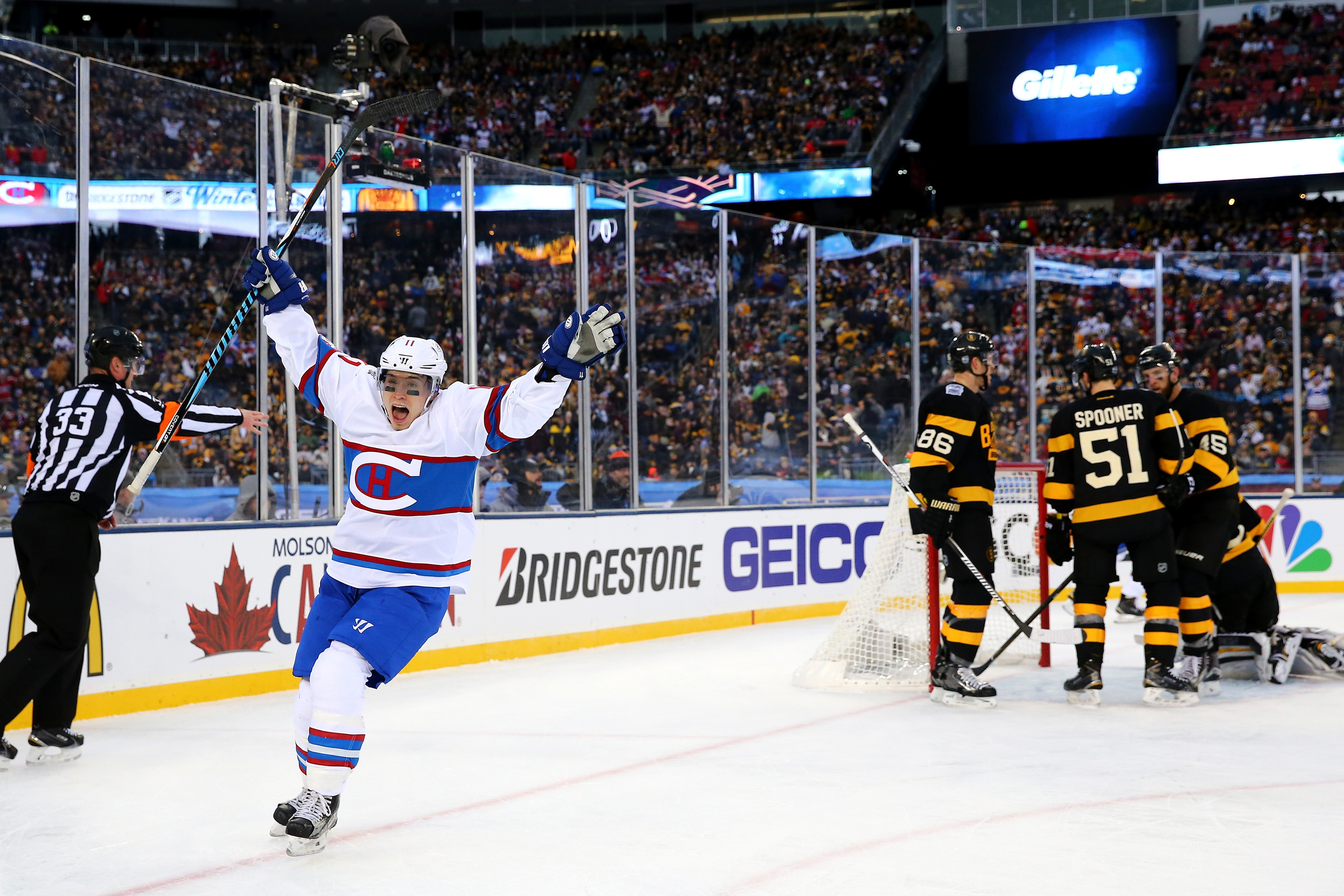 Brendan Gallagher celebrates on the ice with Bruins players around their goalie.