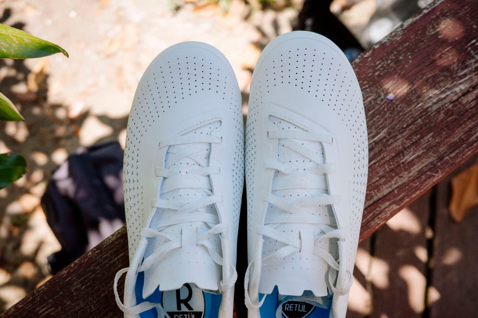 Pair of white cycling shoes on a wooden surface Pair of white cycling shoes on a wooden surface