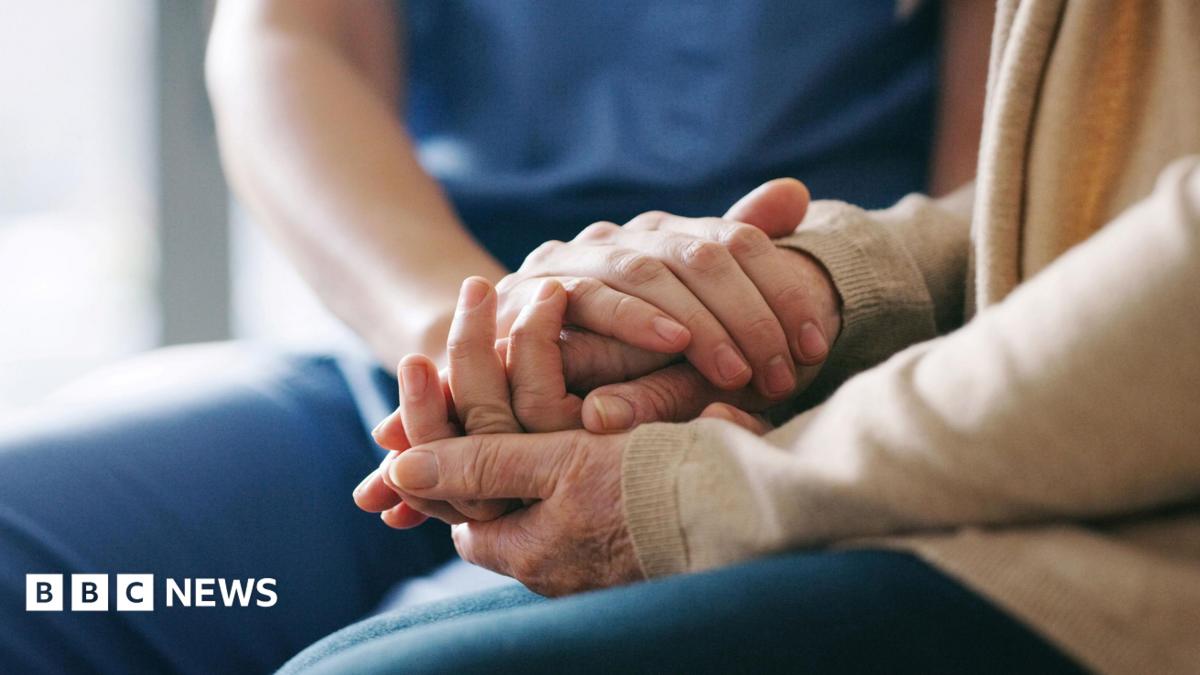 A stock photo of a close up of two people holding hands in a supportive way.