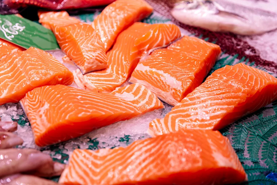 Fresh salmon fillets displayed on ice at a market