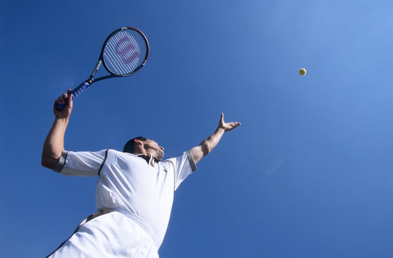 Man throwing a tennis ball in the air during his serve
