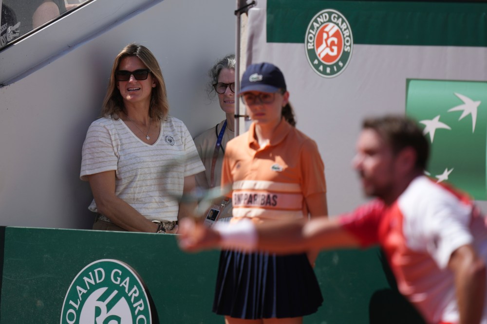 Roland Garros tournament director and former tennis star Amelie Mauresmo, left, watches as Stan Wawrinka of Switzerland, right, returns to Jesper De Jong of the Netherlands during their first round men's singles tennis match at the French Open tennis tournament in Paris, Monday, May 25, 2026. (AP Photo/Thibault Camus)