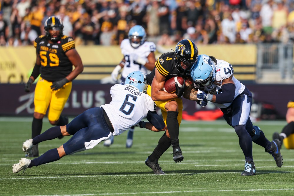 Hamilton Tiger-Cats' Brendan O'Leary-Orange (4) tries to break through Toronto Argonauts teammates Branden Dozier (6) and Wynton McManis (48) during second half CFL Labour Day Classic football action in Hamilton, Ont., Monday, Sept. 1, 2025. THE CANADIAN PRESS/Nick Iwanyshyn