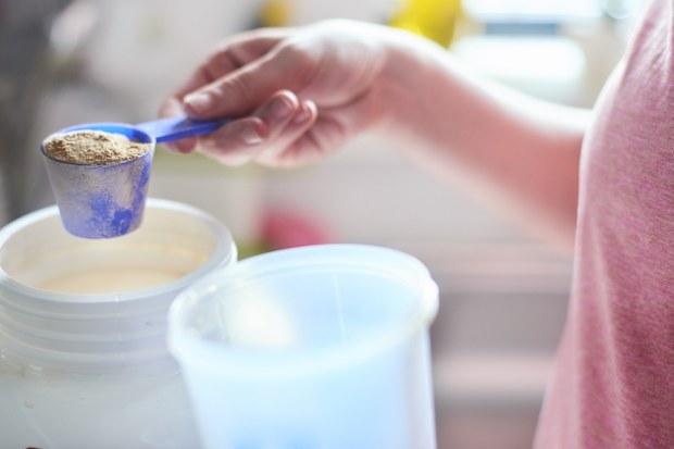 Measuring out protein powder with a measuring scoop from the container