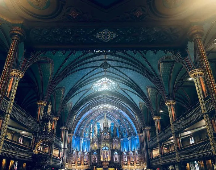 Ornate interior of a grand cathedral with intricate arches and a large illuminated altar in the center