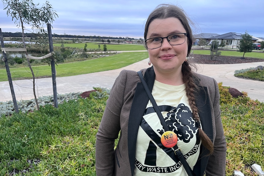 A woman wearing a yellow shirt and brown jacket.