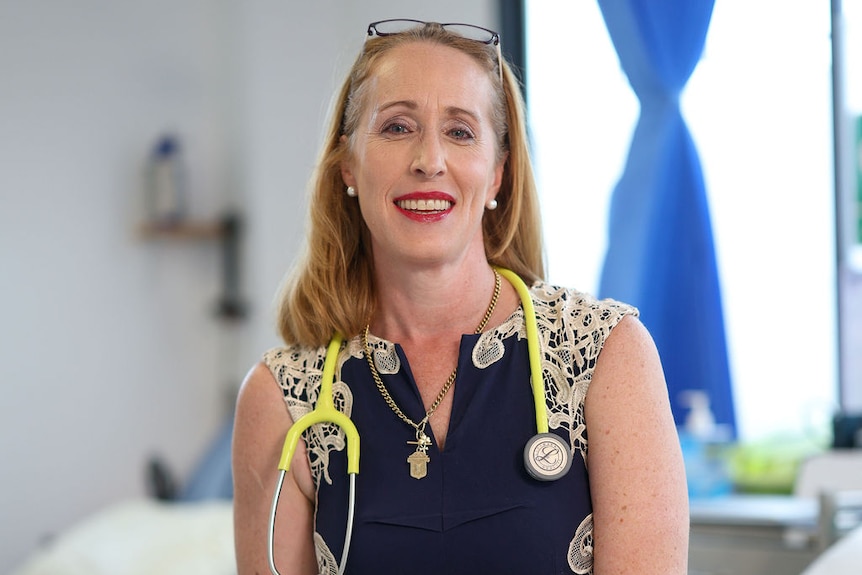 Erica Gannon wears a blue dress and has a stethoscope around her neck.