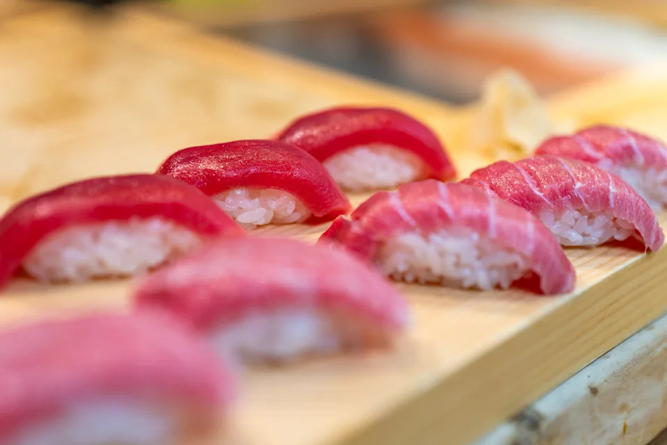 Sushi pieces on a wooden board, featuring tuna on rice. Image relates to health benefits of sushi in the article