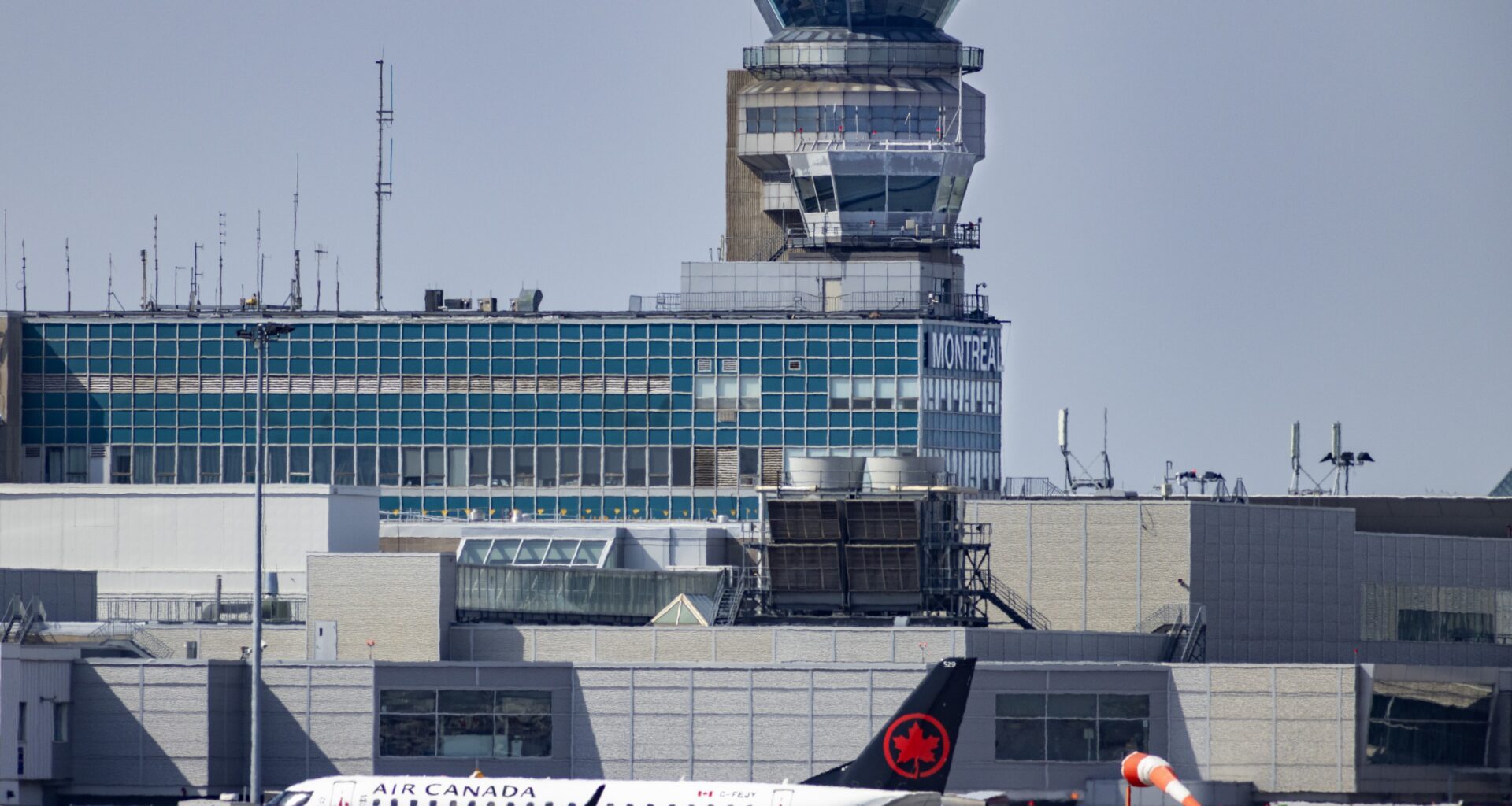 An Air Canada jet is seen with the Montreal airport control tower in the background.