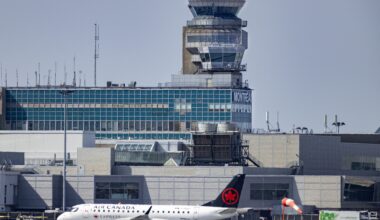 An Air Canada jet is seen with the Montreal airport control tower in the background.