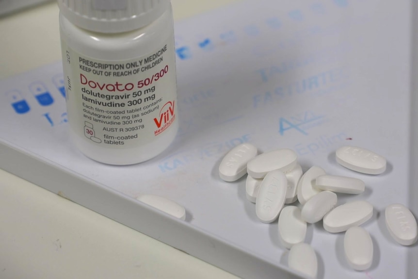 White pills spilling out of a box onto a white tabletop