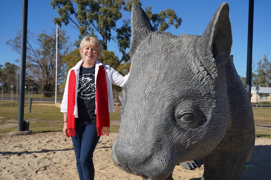 A woman leans on a wombat statue