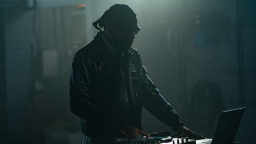 A musician is using a laptop and mixing gears to create music. 