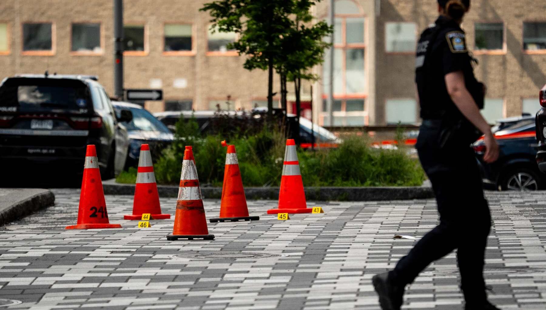 Photo of a police officer walking outside with orange cones in the background.
