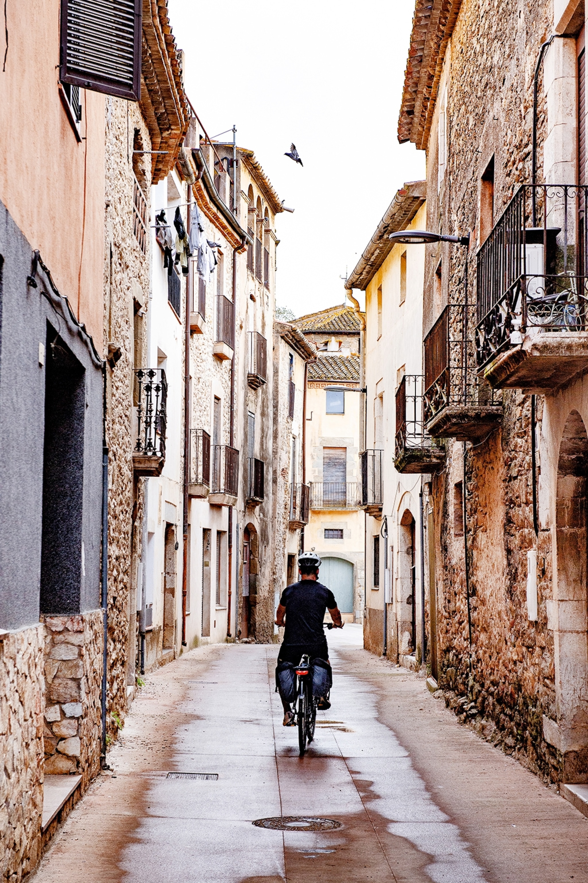 Cyclist heading down narrow backstreet.