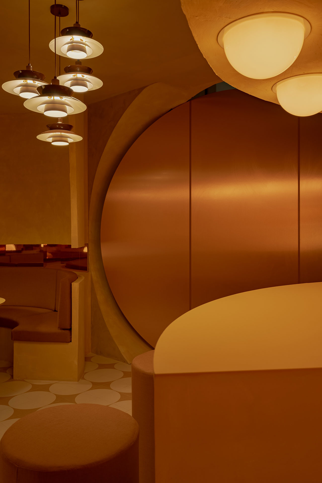 A modern interior with warm lighting, round seating, geometric wall décor, and circular pendant lights, featuring a minimalist, gold and beige color scheme.