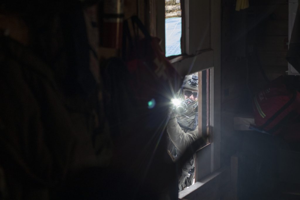 A militarized police officer aims his gun into a tiny house full of unarmed individuals on Friday, Nov. 19, 2021.