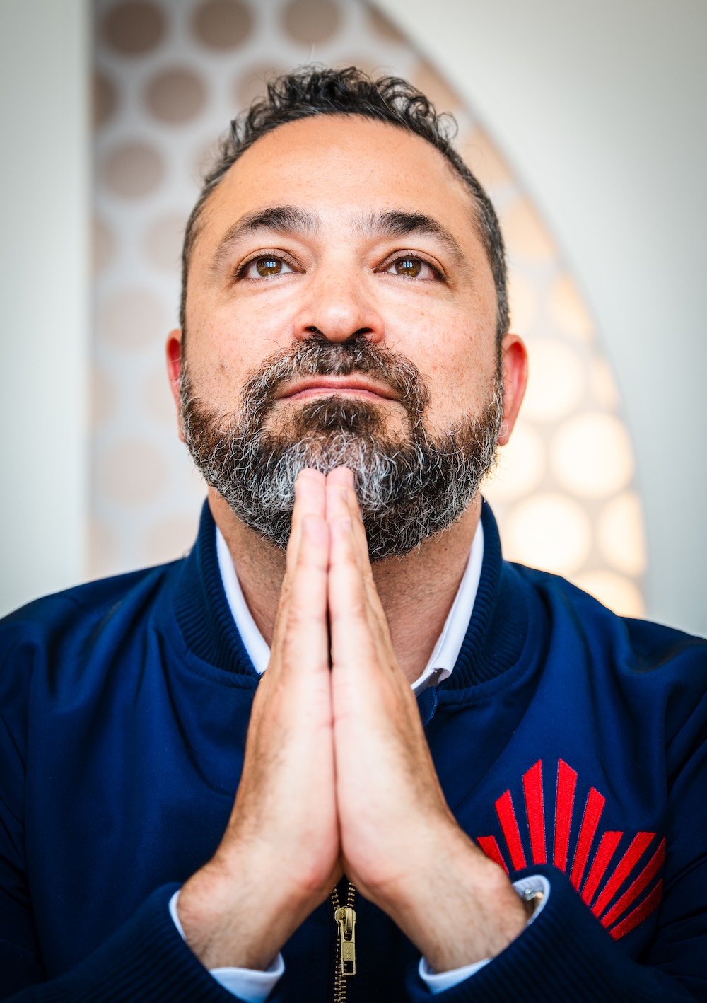 A close-up of Daniel Sax with his hands steepled under his chin, as if he's praying.