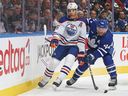  Darnell Nurse #25 of the Edmonton Oilers flips the puck away against Morgan Rielly. 

Getty Images)