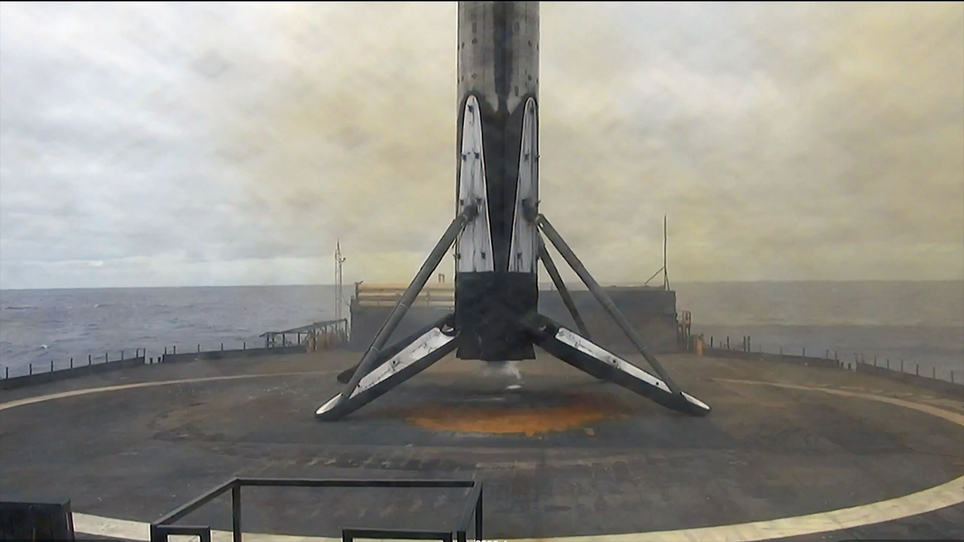 the first stage of an orbital rocket stands on its four landing legs atop an ocean-based platform