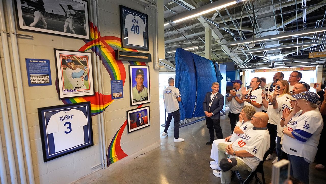 Attendees reacts during a ceremony prior to a baseball game to unveil a tribute to LGBTQ+ trailblazers and former Los Angeles Dodgers players Billy Bean and Glenn Burke, who were among the first professional athletes to identify as gay, Friday, June 5, 2026, in Los Angeles. (AP Photo/Mark J. Terrill)
