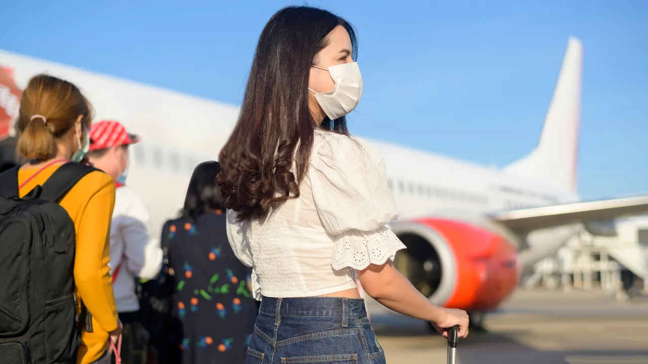 Masked travelers wait near a plane before World Cup travel