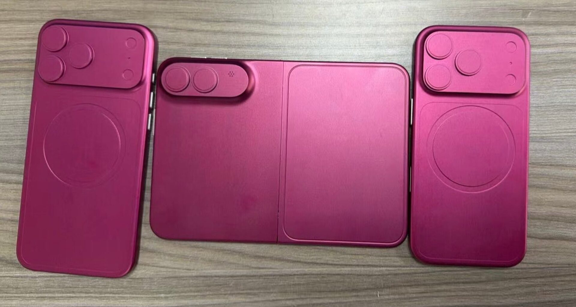 Three pink magenta phone cases laid out on a wooden surface, showing camera cutouts and a foldable center panel (wallet style).