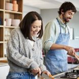 Man Cooking By Woman Chopping Carrots In Kitchen - stock photo