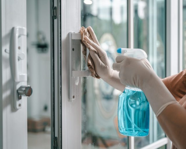 Deep cleaning glass door handles for Covid-19 disease prevention. alcohol,disinfectant spray on Wipes of Banister in home for safety,infection of Covid-19 virus,contamination, germs - stock photo