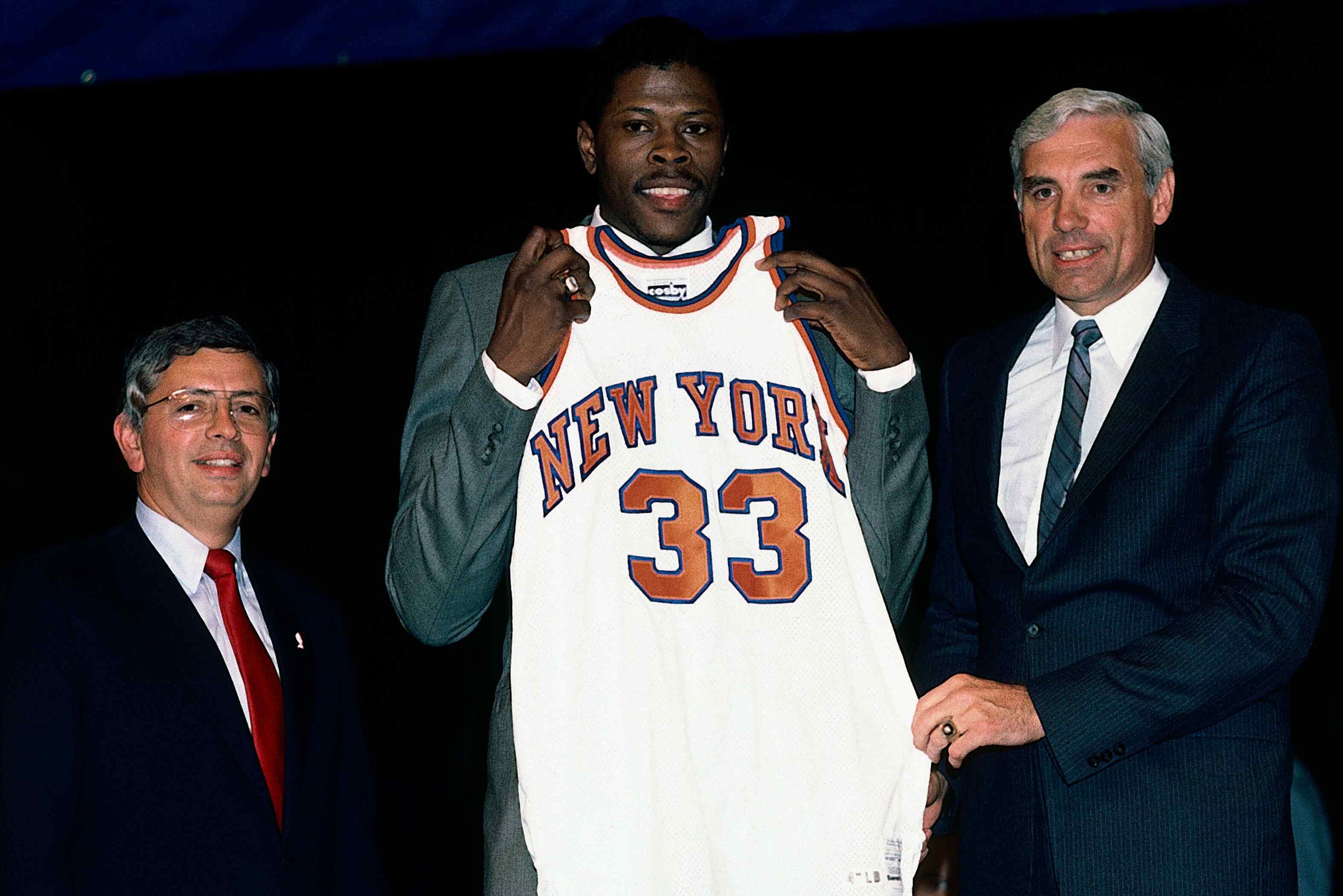 Patrick Ewing holds up his new Knicks jersey with the Knicks general manager Dave DeBusschere and NBA commissioner David Stern in 1985 draft. (Noren Trotman / NBAE / Getty Images)